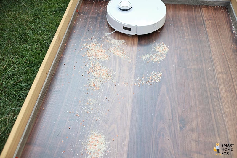 ECOVACS DEEBOT T10 reinigt Haferflocken auf einem Laminatboden im Saugtest.